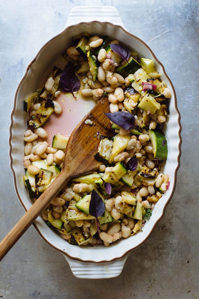 A dish of white bean salad with grilled zucchini, shallots, basil and oregano. 