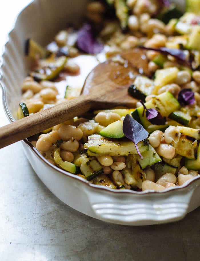 White bean salad with grilled zucchini, fresh herbs, shallots and oregano in a shallow dish.