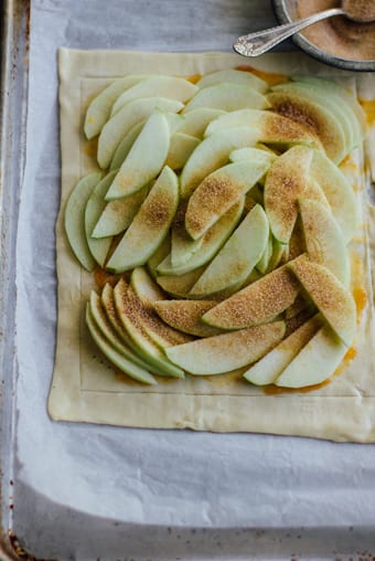 Sliced Granny Smith Apples on a sheet of puff pastry with cinnamon-sugar