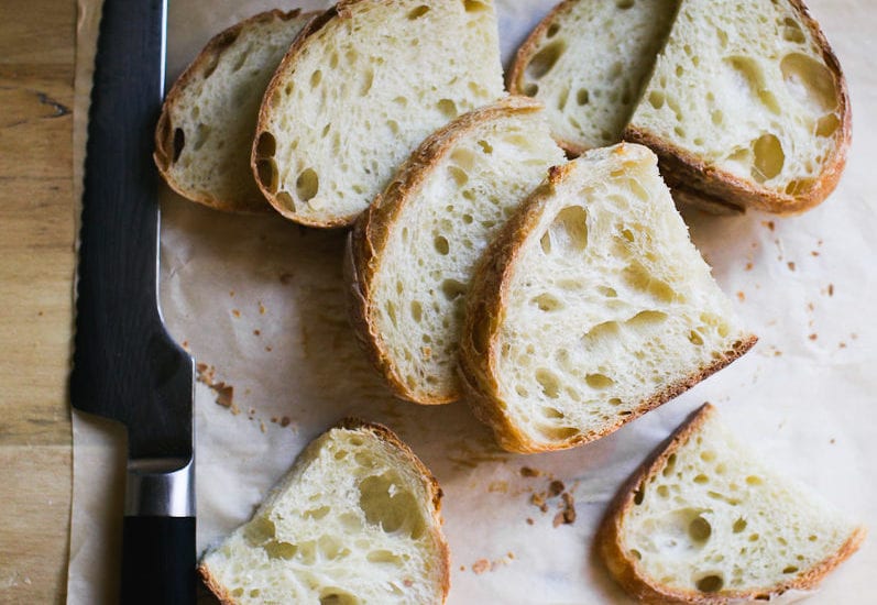 Sourdough bread slices on top of parchment paper with a bread knife