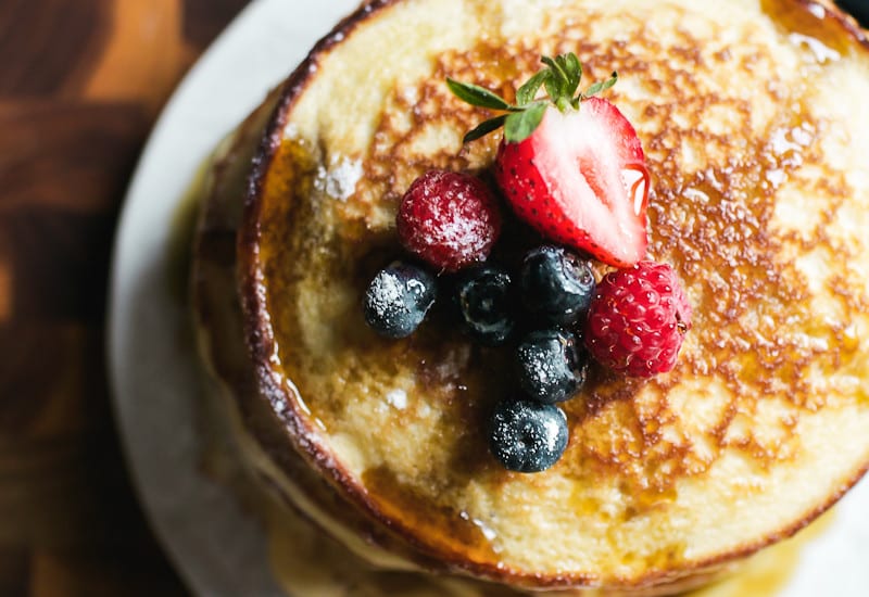Stack of light and fluffy sourdough discard pancakes with fruit on top