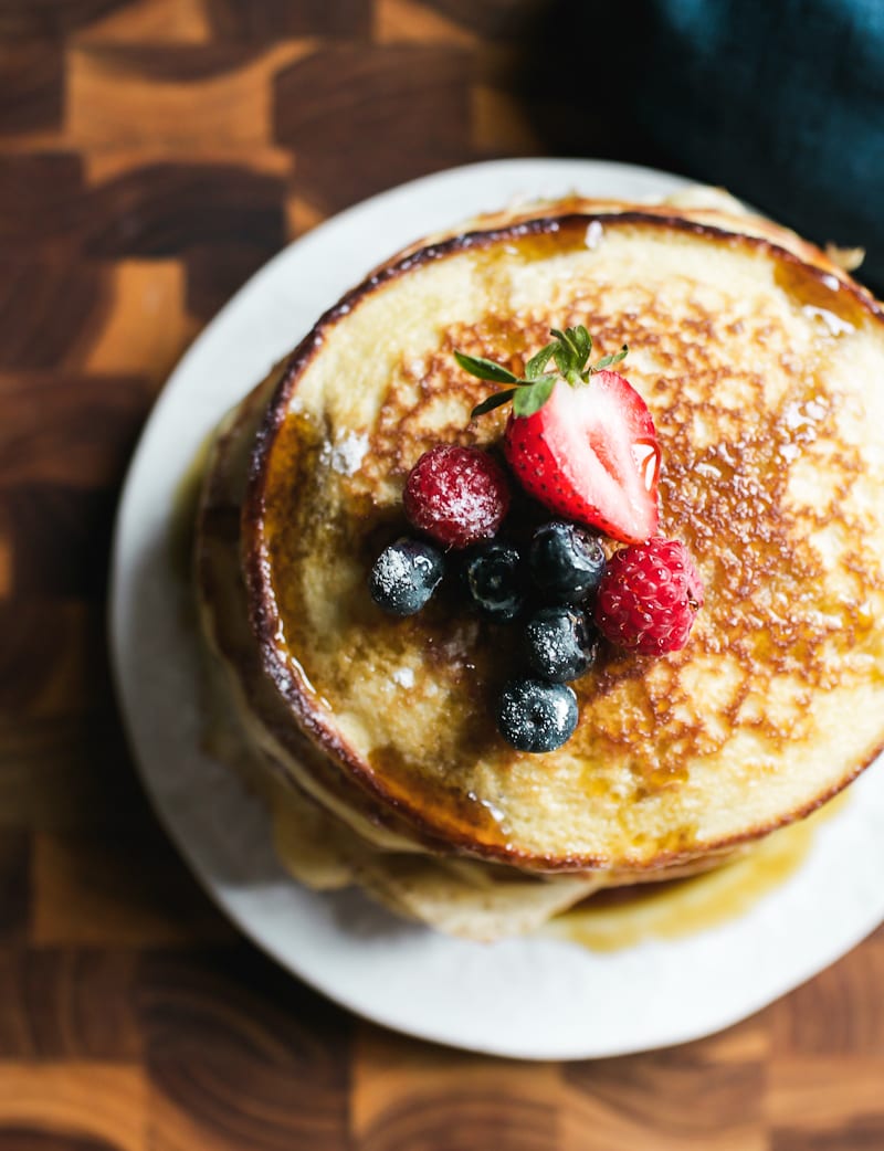 Stack of light and fluffy sourdough discard pancakes with fruit on top