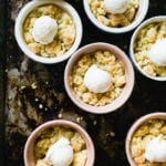 Small individual ramekins with apple crumble and scoops of vanilla ice cream