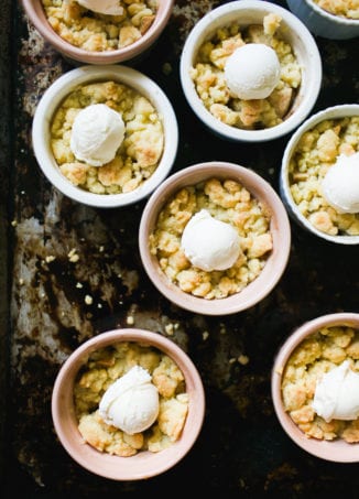Small individual ramekins with apple crumble and scoops of vanilla ice cream