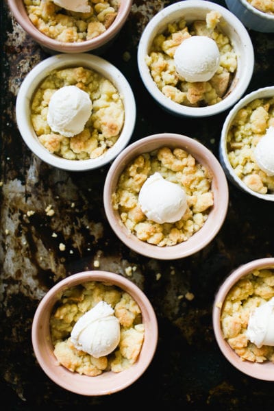 Small individual ramekins with apple crumble and scoops of vanilla ice cream