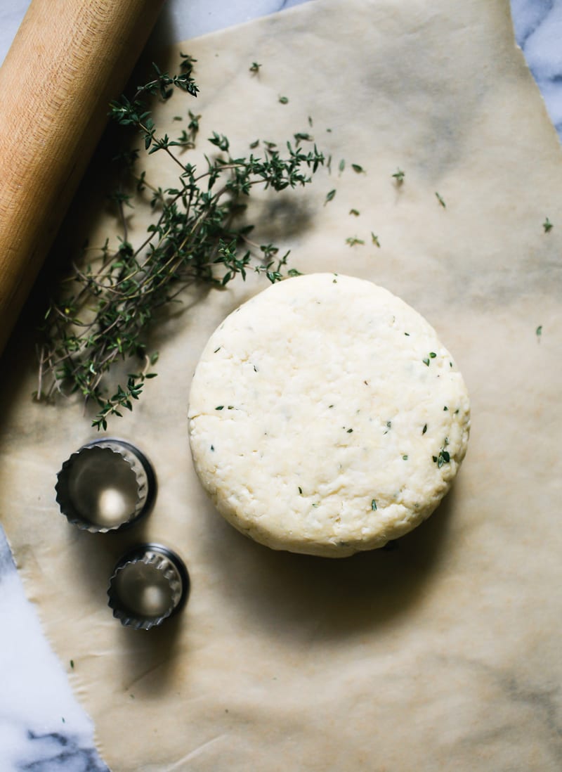 Flattened disc of homemade sourdough cracker dough with fresh thyme