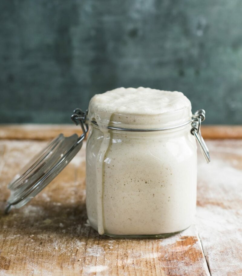 Fed, active sourdough starter in a latch-top jar on a wooden surface