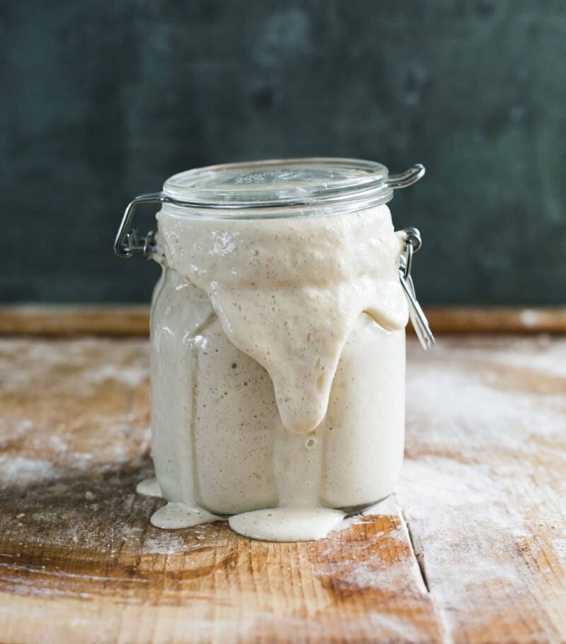 jar of bubbly, active sourdough starter on a wooden surface
