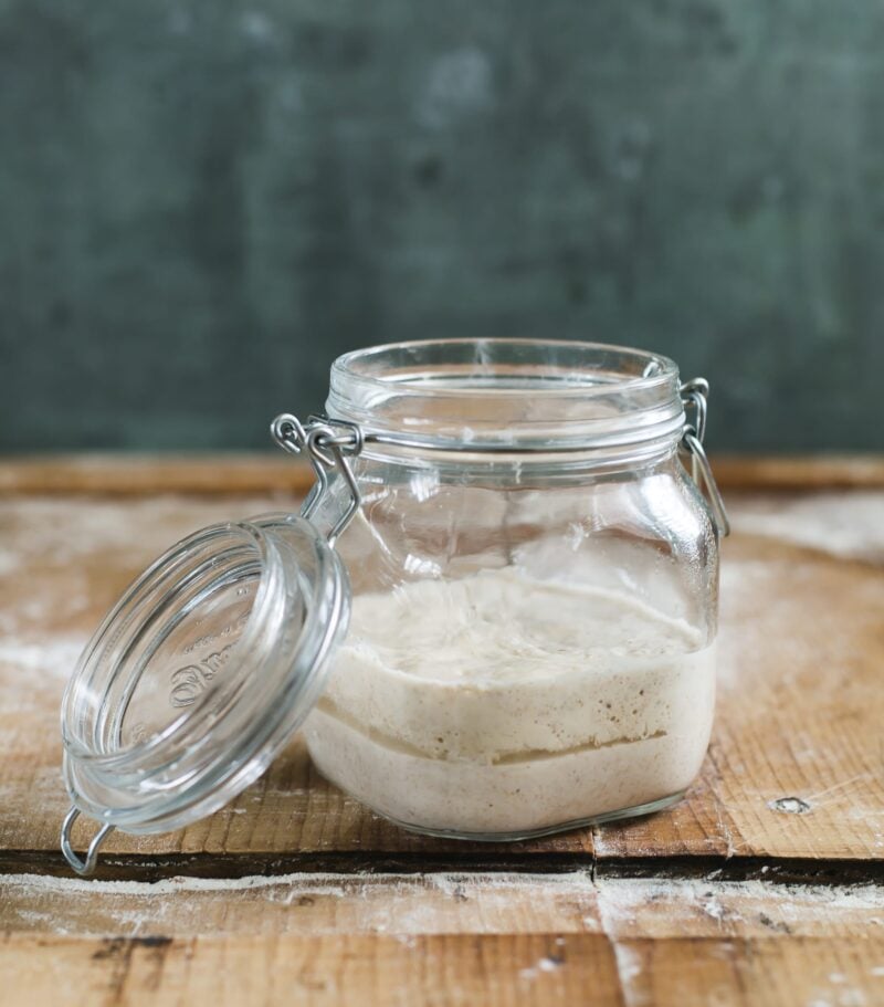 Jar of unfed sourdough starter on a wooden surface