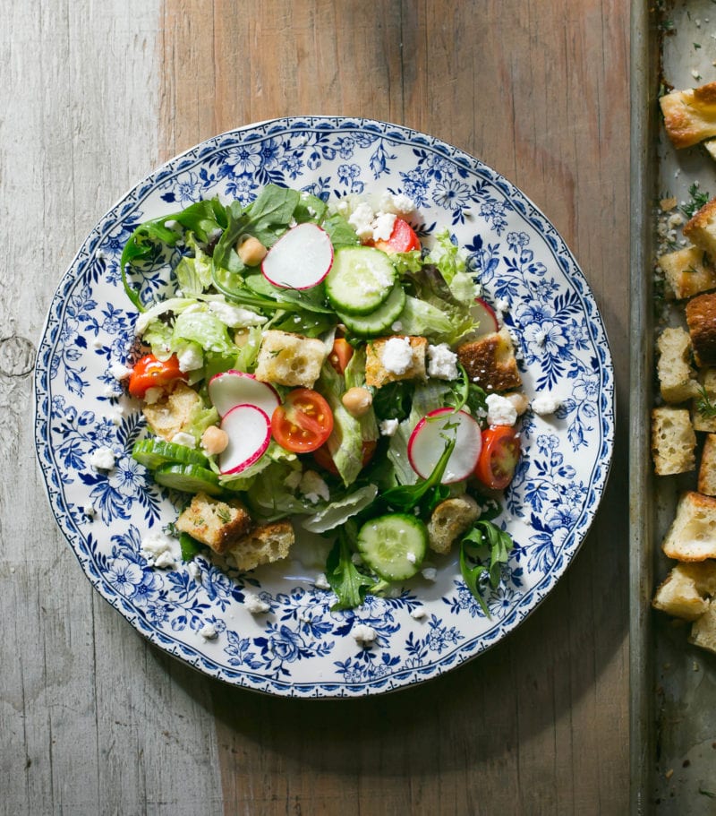 Colorful Greek salad with sourdough croutons on a blue plate
