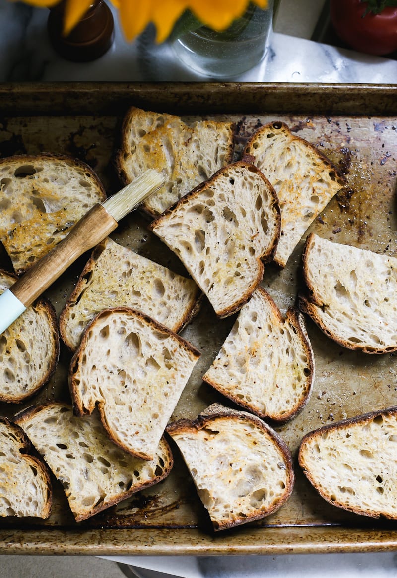 Sliced sourdough bread, lightly oiled, on a sheet pan