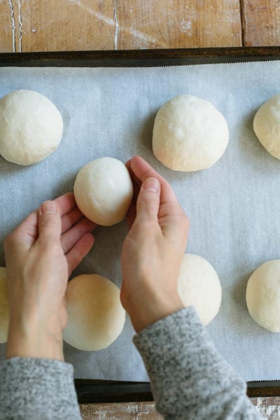 Sourdough bagel dough, shaped into small balls, on a parchment-lined sheet pan.