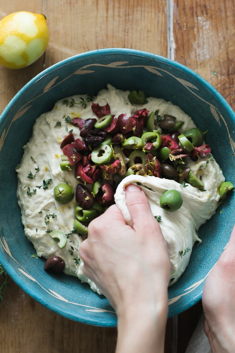 Bowl of dough with olives, thyme, rosemary and parmesan