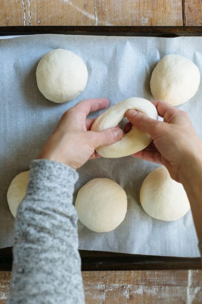 Stretching and shaping sourdough bagel dough.