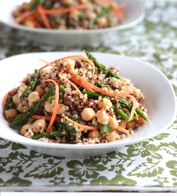 White bowl of curried quinoa with asparagus, chickpeas and shredded carrots.
