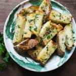 Green and white bowl with sliced garlic bread with sesame seeds