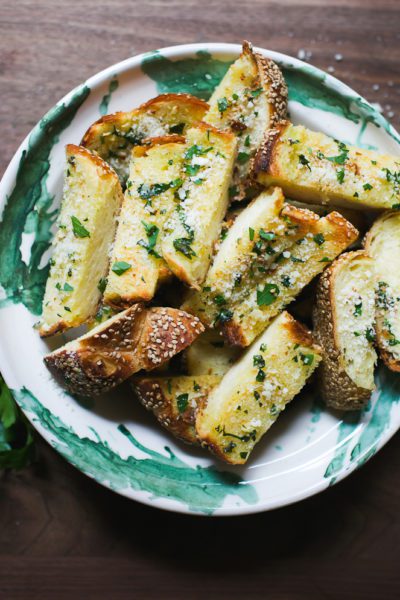 Green and white bowl with sliced garlic bread with sesame seeds