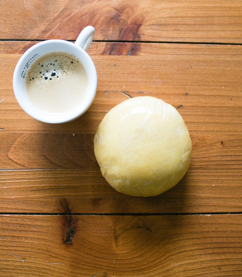 Ball of dough wrapped in plastic wrap with an espresso on the side.
