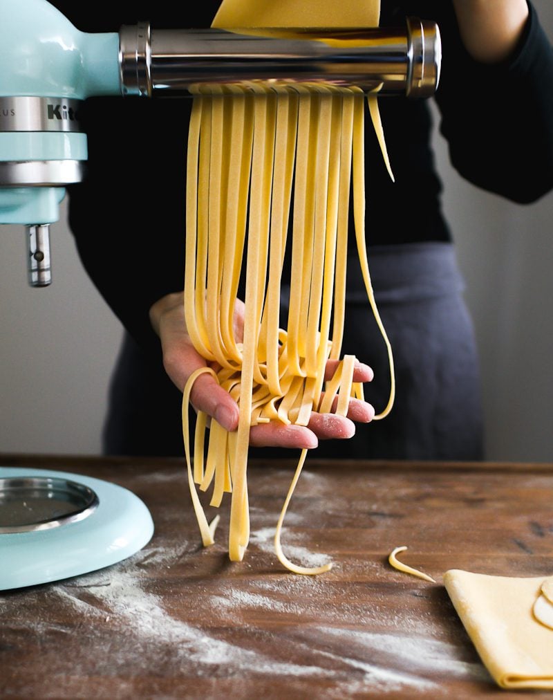 Long fettuccini strands, fresh pasta, coming through the Kitchen Aid stand mixer pasta attachment.