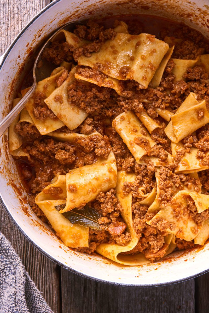 Fresh homemade pappardelle pasta with Ragù Bolognese sauce in a Dutch oven pot