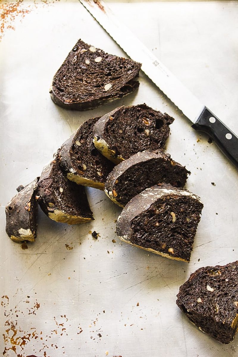 Chocolate sourdough bread slices on a tray with a bread knife