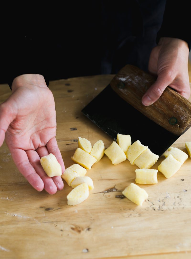 A pile of gnocchi on a wooden cutting board.