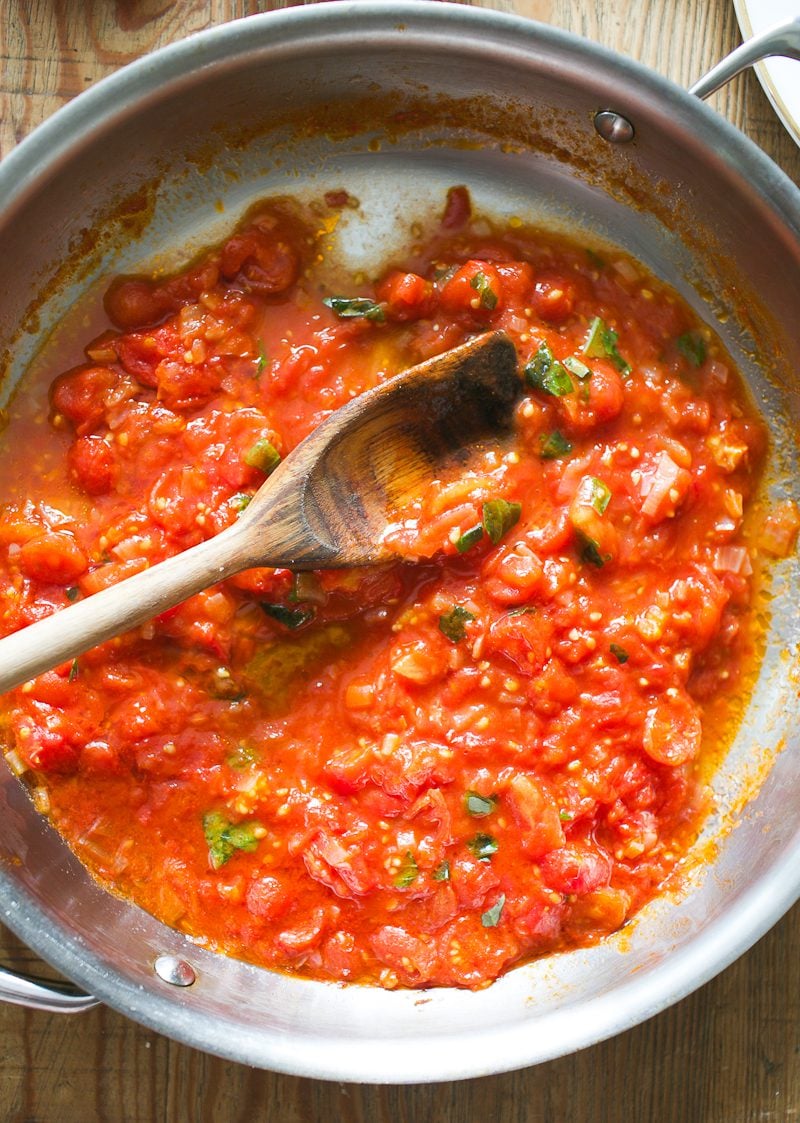 Pomodoro sauce in a pan with a wooden spoon.