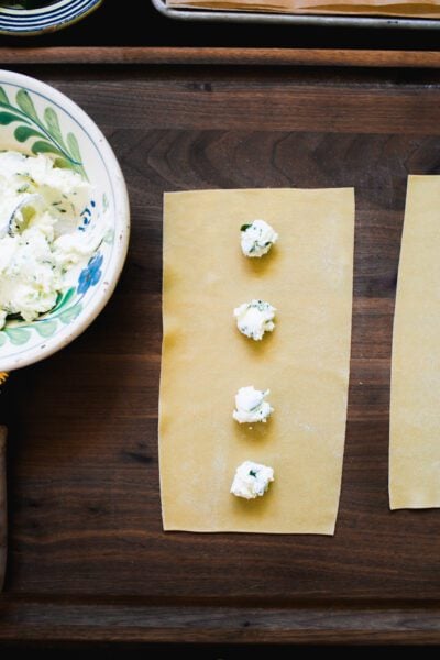 Fresh homemade pasta sheet with dollops of ravioli cheese filling down the center.