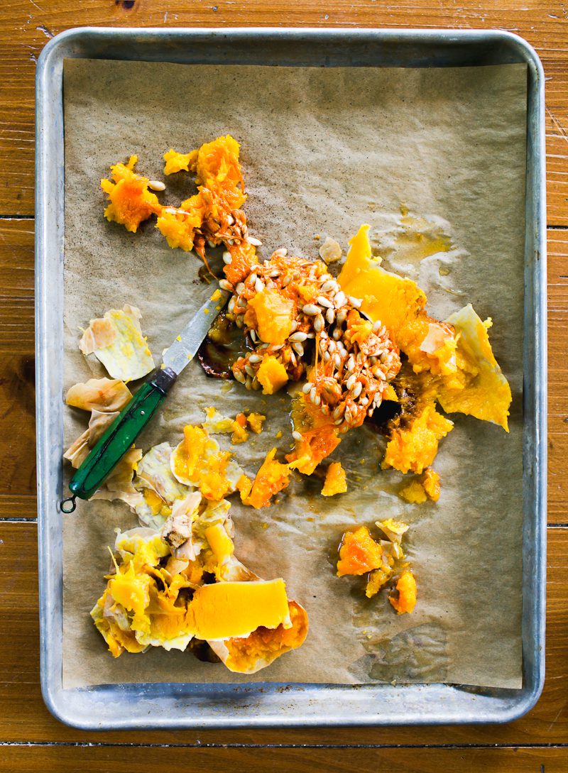 Whole-roasted butternut squash, fully peeled, with seeds and scraps on a parchment-lined sheet pan 