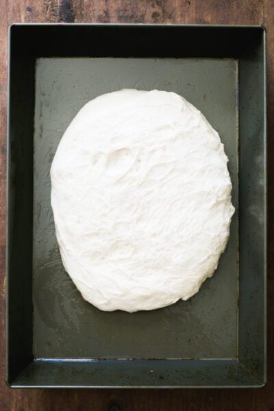 Sourdough pizza dough in a non-stick baking pan