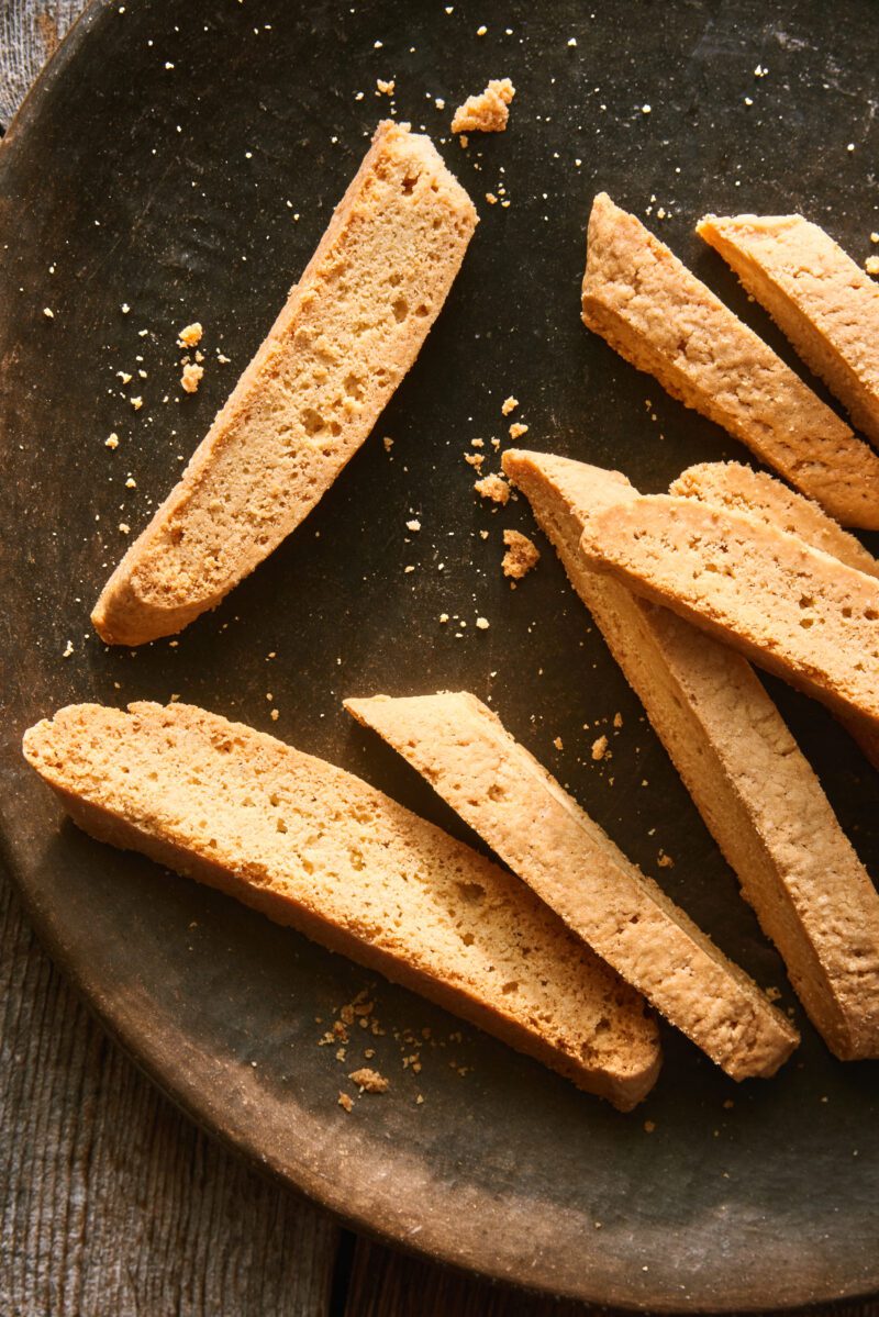 Anise biscotti on a black plate with cookie crumbs