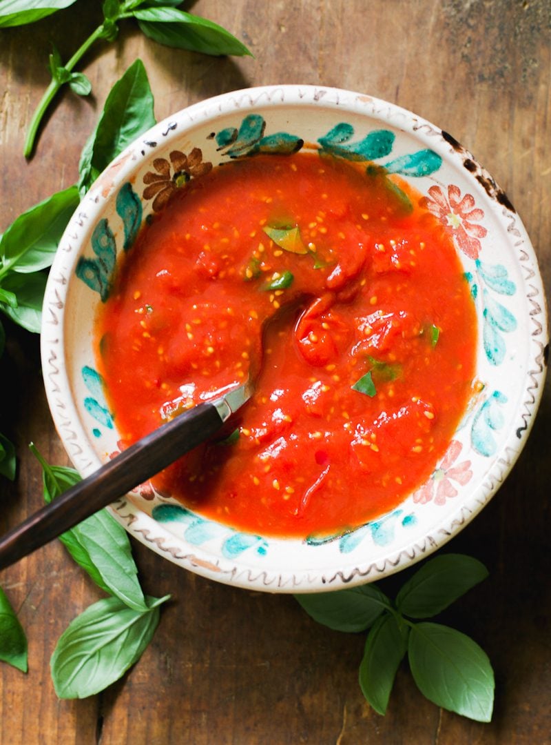 Quick no-cook pizza sauce in a bowl with fresh basil