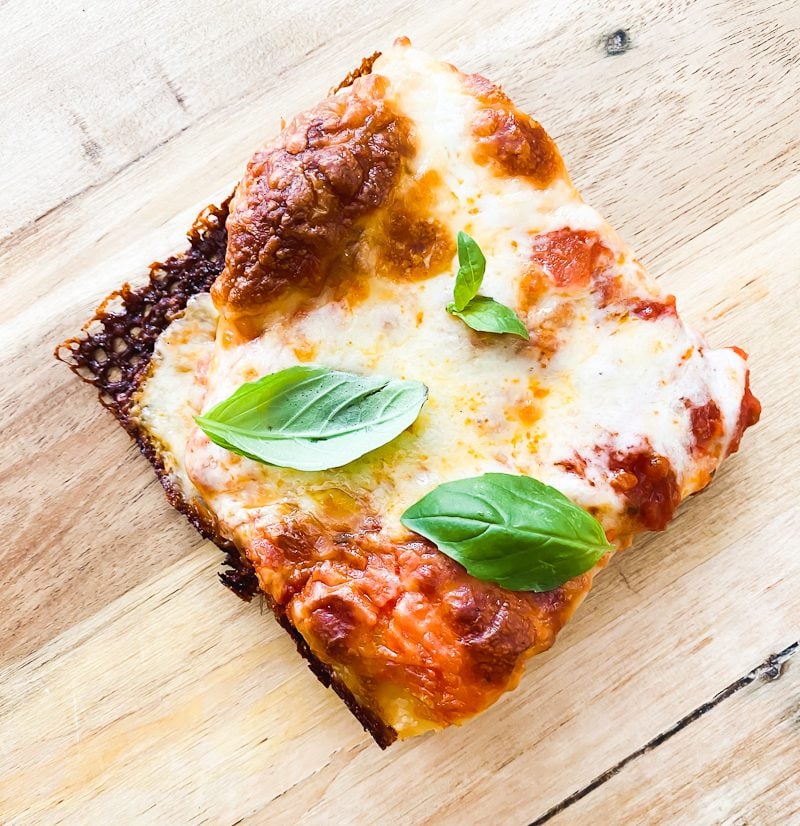 Sourdough pizza slice, with tomato sauce, mozzarella cheese and crispy, cheesy edges