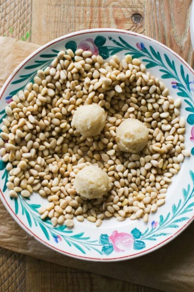 Pignoli cookie dough balls in a bowl of pignoli nuts