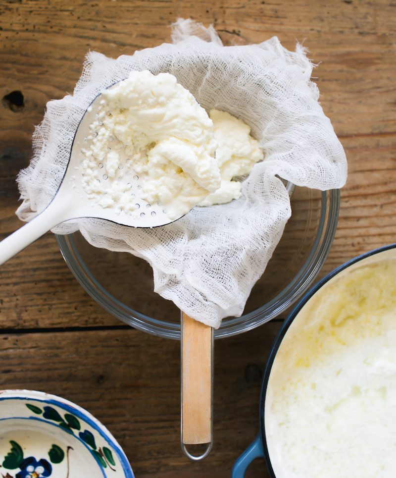 Ricotta curds in a cheesecloth lined strainer