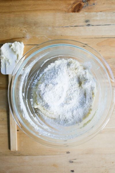 Flour with ricotta mixture in a glass mixing bowl with a rubber spatula