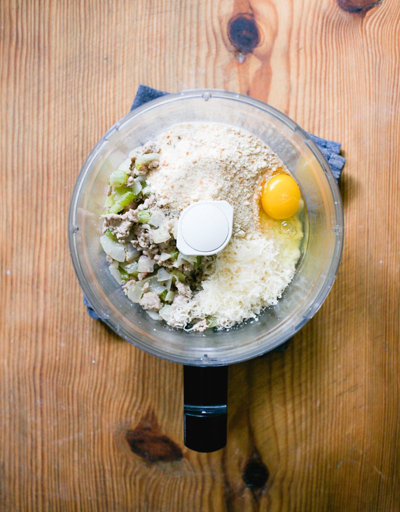 Ground pork meat filling in a food processor with Parmesan cheese, egg, and breadcrumbs.