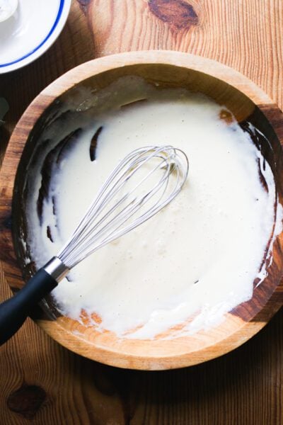 Whisked wet ingredients in a wooden bowl: egg, sourdough starter, vanilla extract and zest, if using.