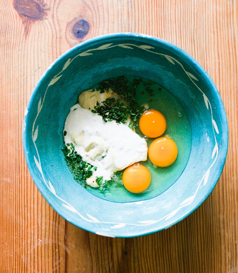 Eggs, sourdough starter, mustard, parsley and spices in a blue mixing bowl