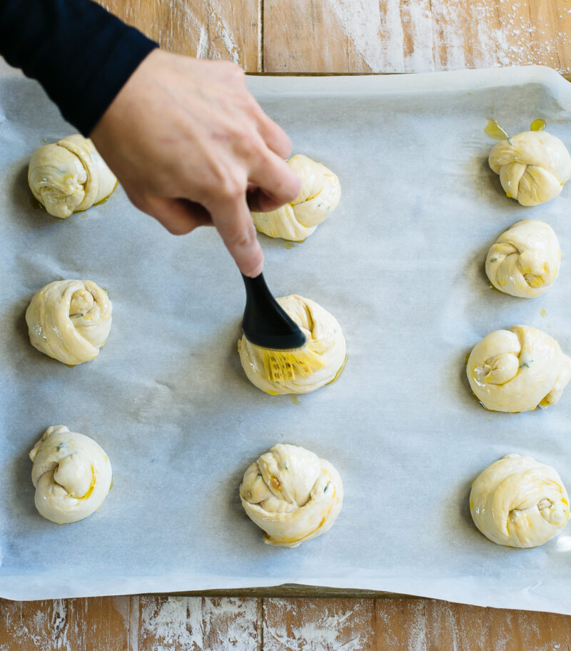 Brushing unbaked sourdough garlic knots with olive oil