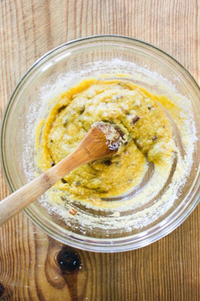 Whisked eggs, grated cheese, guanciale drippings and black pepper mixed together in a glass mixing bowl.