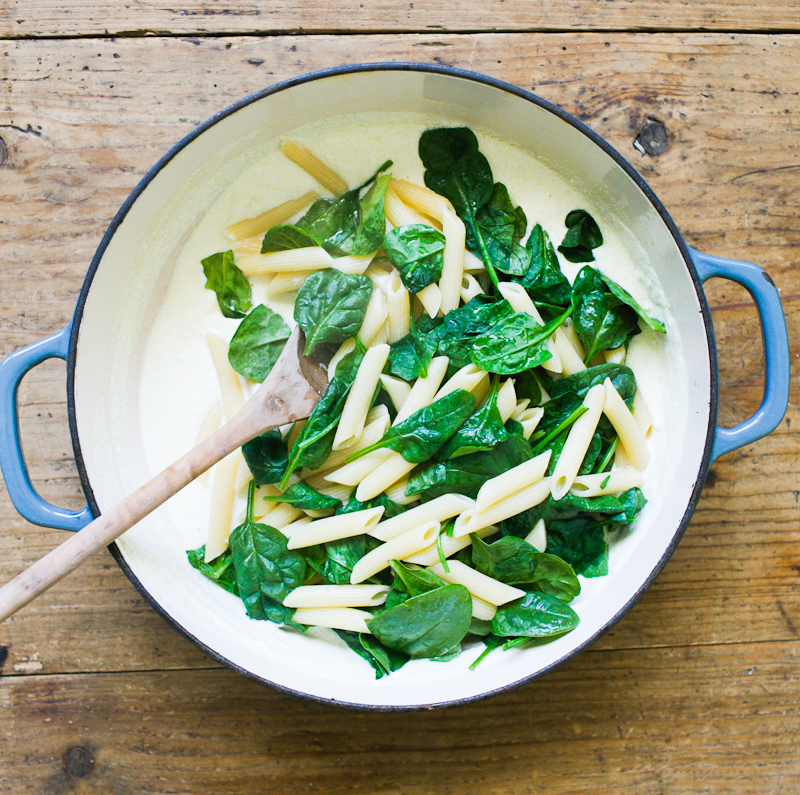 Braiser pot with creamy, homemade ricotta sauce, penne pasta and wilted baby spinach