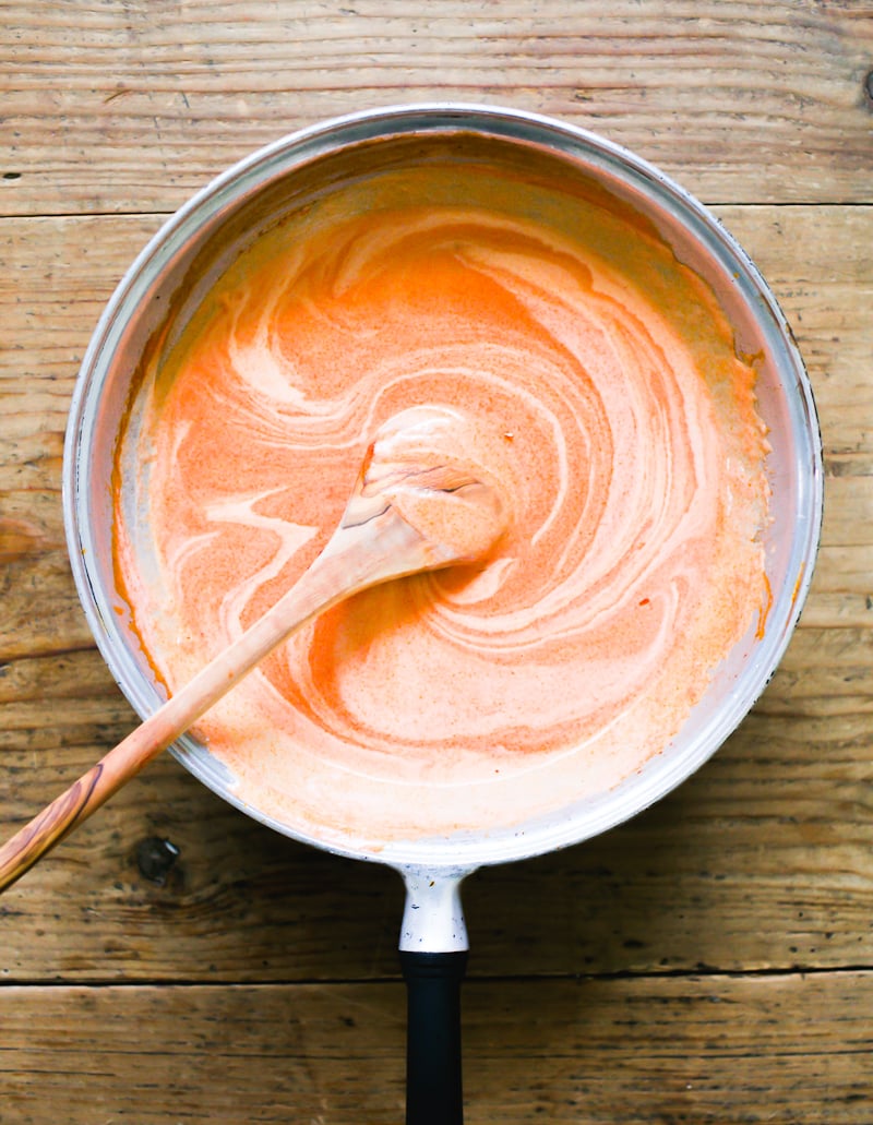 Tomato paste and cream stirred together in a pan to form a luscious sauce