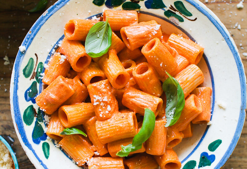 Rigatoni pasta with vodka sauce in a bowl with fresh basil and Parmesan cheese
