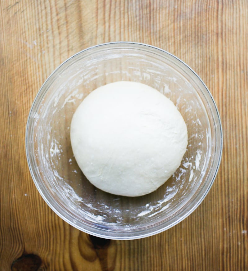 Glass mixing bowl with a ball of sourdough English muffin dough