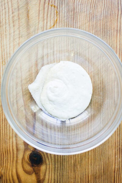 Active sourdough starter and sugar in a glass mixing bowl