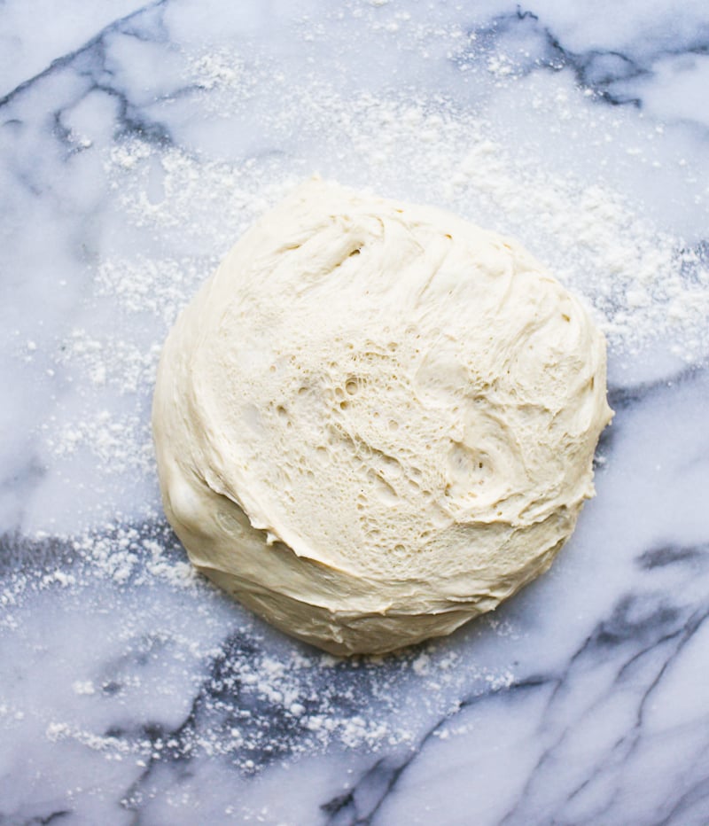 Sourdough English muffins dough after the bulk rise on a marble surface