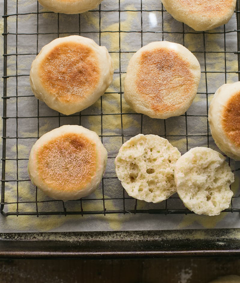 Sourdough English muffins on a vintage wire rack, sliced open to expose a beautiful, craggy-holed interior crumb.