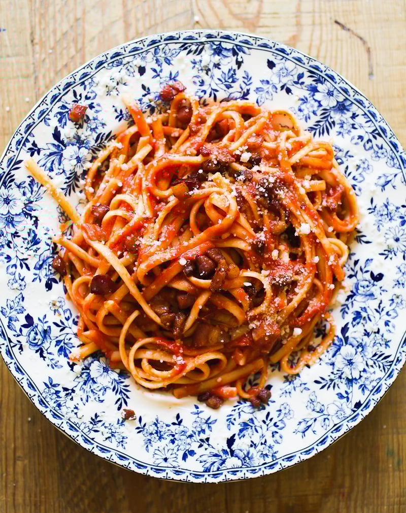 Pasta all"Amatriciana with crispy guanciale on a white and blue plate.