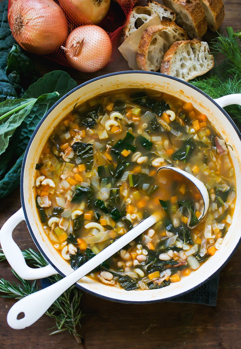 Italian Minestrone soup in a white pot with crusty sourdough bread on the side